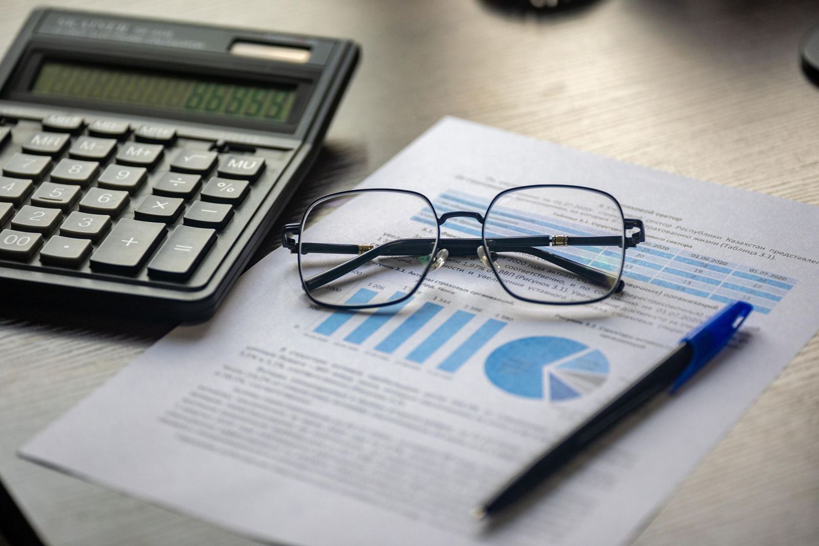 Company documents with a calculator and reading glasses on a desk
